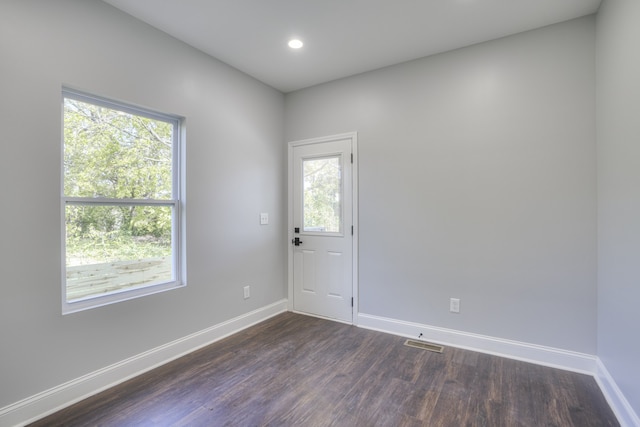 empty room featuring plenty of natural light and dark hardwood / wood-style flooring