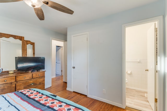 bedroom with ceiling fan, light wood-type flooring, ensuite bathroom, and tile walls