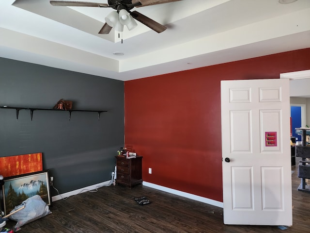 bedroom with a raised ceiling, dark hardwood / wood-style floors, and ceiling fan