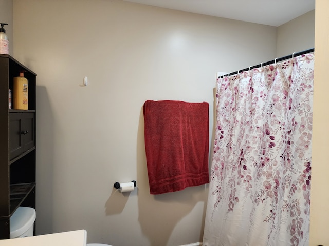 bathroom with toilet and a shower with shower curtain