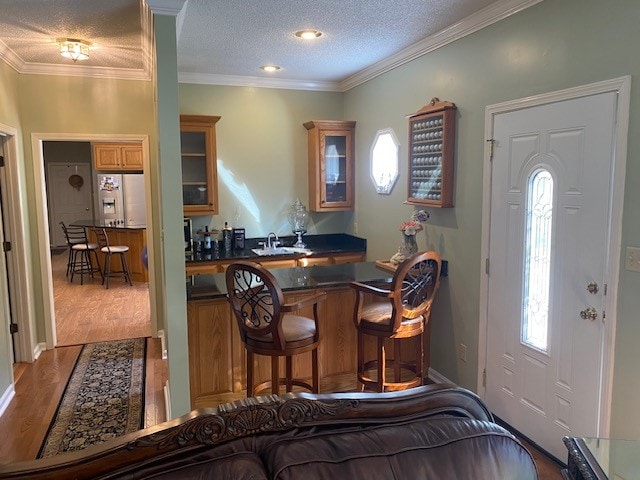 interior space featuring light hardwood / wood-style flooring, a textured ceiling, and ornamental molding