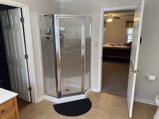 bathroom featuring vanity, crown molding, ceiling fan, a shower with door, and tile patterned floors