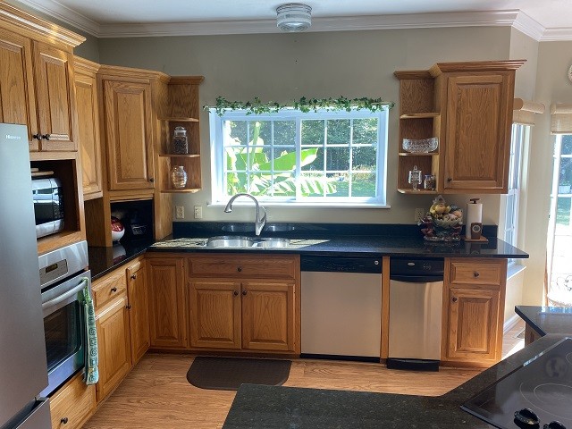 kitchen with ornamental molding, stainless steel appliances, light hardwood / wood-style floors, and sink