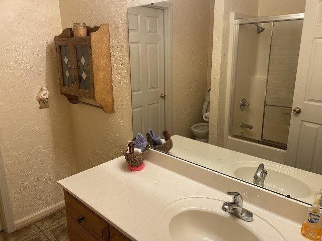 full bathroom with shower / bath combination with glass door, vanity, and toilet