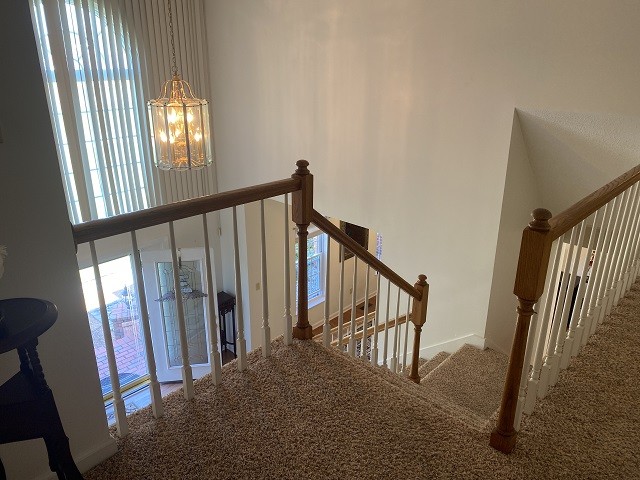 staircase featuring carpet floors and a chandelier