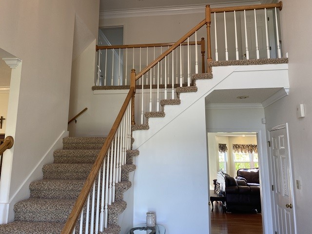 stairs with ornamental molding, decorative columns, and hardwood / wood-style floors