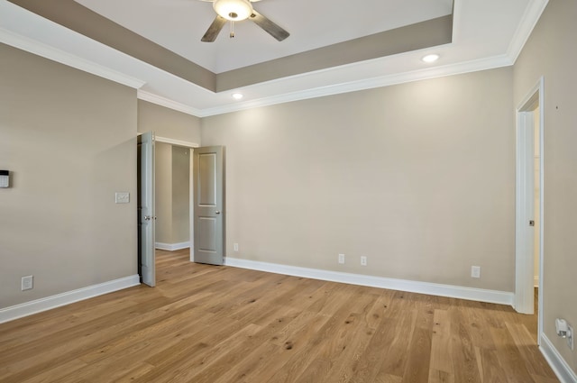 unfurnished bedroom with light hardwood / wood-style flooring, a tray ceiling, ceiling fan, and crown molding