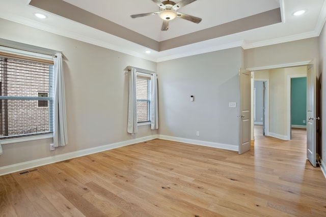 unfurnished room with crown molding, light hardwood / wood-style floors, a tray ceiling, and ceiling fan