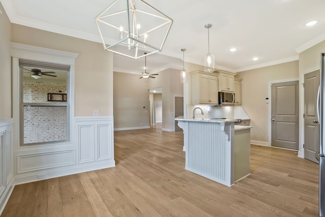 kitchen with a breakfast bar, hanging light fixtures, decorative backsplash, light hardwood / wood-style flooring, and ornamental molding