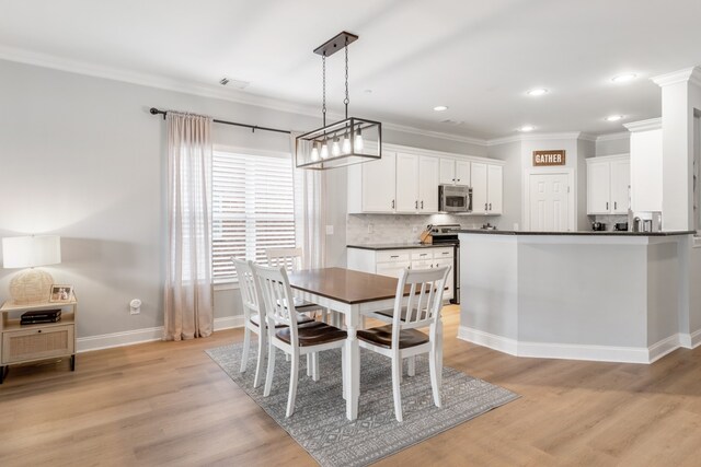 dining room with ornamental molding and light hardwood / wood-style floors