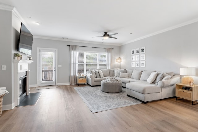 living room featuring a fireplace, ornamental molding, ceiling fan, and light hardwood / wood-style flooring