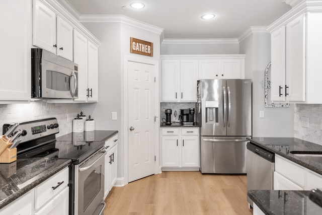 kitchen with light hardwood / wood-style flooring, stainless steel appliances, white cabinetry, and backsplash