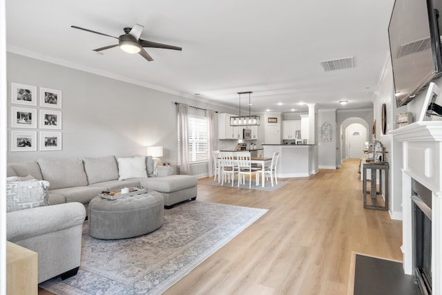 living room featuring crown molding, light hardwood / wood-style floors, and ceiling fan