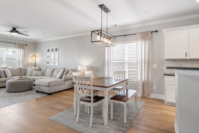 dining room with ceiling fan with notable chandelier, light hardwood / wood-style flooring, and ornamental molding