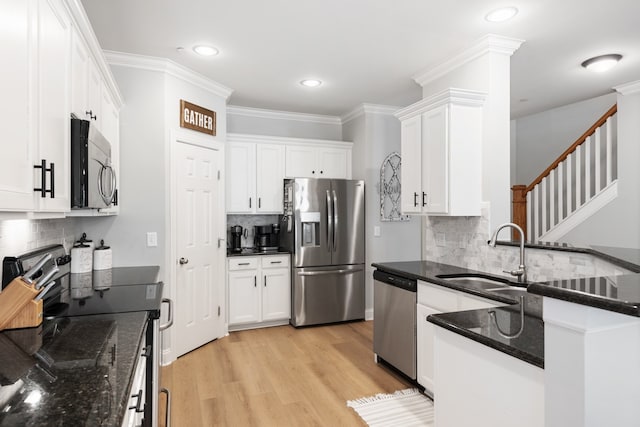 kitchen featuring sink, white cabinetry, appliances with stainless steel finishes, dark stone countertops, and light wood-type flooring