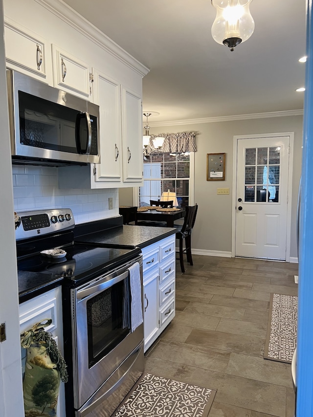 kitchen featuring white cabinets, ornamental molding, decorative light fixtures, backsplash, and appliances with stainless steel finishes