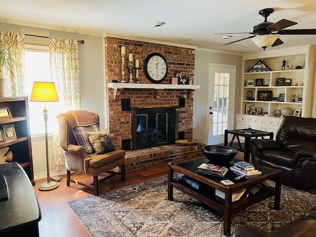 living room featuring hardwood / wood-style flooring, a fireplace, crown molding, and a healthy amount of sunlight