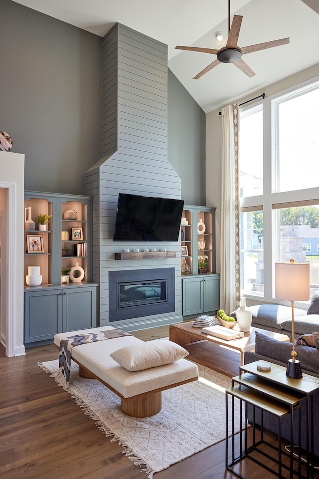 living room featuring dark hardwood / wood-style floors, a large fireplace, ceiling fan, and high vaulted ceiling