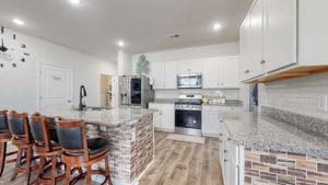 kitchen featuring stainless steel appliances, white cabinetry, light stone counters, and light wood-type flooring