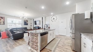 kitchen with a notable chandelier, white cabinetry, light hardwood / wood-style flooring, a center island with sink, and appliances with stainless steel finishes