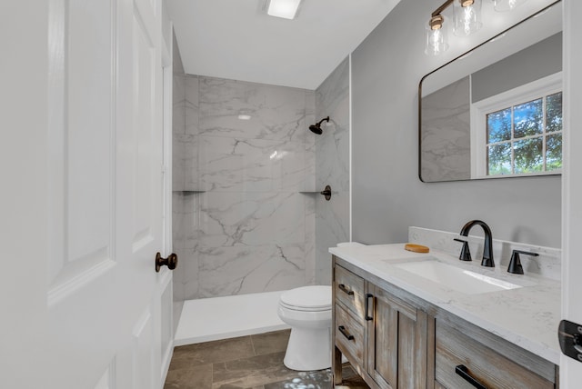 bathroom featuring toilet, vanity, and tiled shower