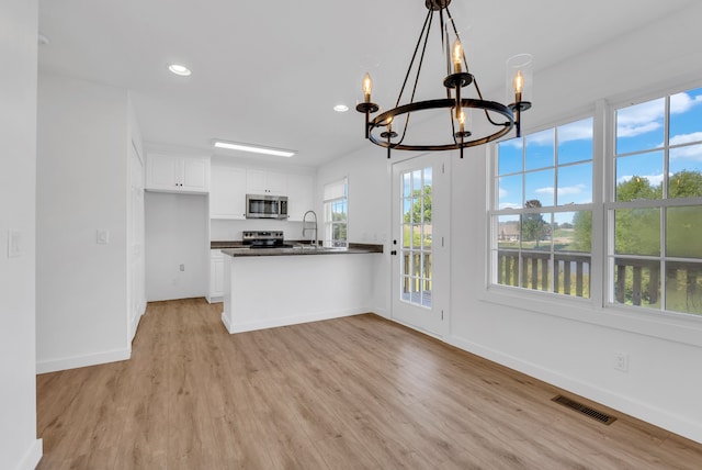 kitchen featuring appliances with stainless steel finishes, light hardwood / wood-style floors, white cabinetry, and kitchen peninsula