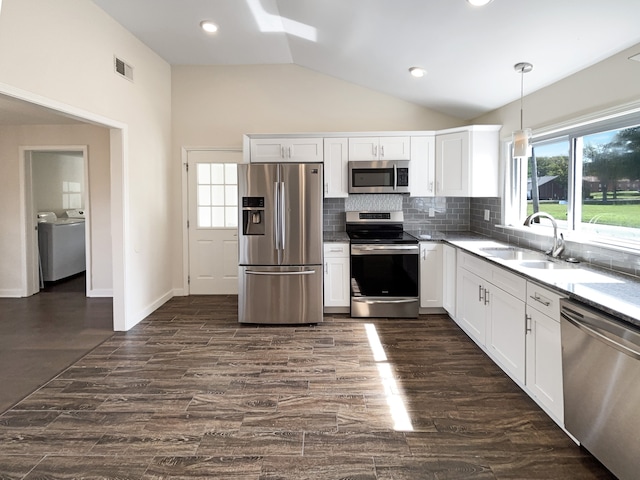 kitchen featuring pendant lighting, sink, white cabinetry, stainless steel appliances, and washing machine and dryer