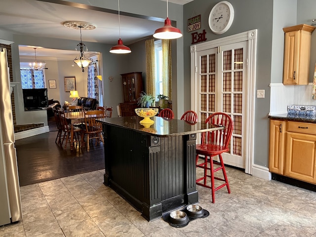 kitchen with light hardwood / wood-style floors, a breakfast bar area, light brown cabinetry, ornamental molding, and a chandelier