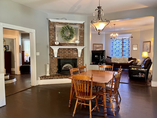 dining area featuring crown molding, a fireplace, and dark wood-type flooring