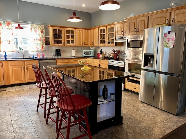 kitchen with sink, a kitchen island, decorative light fixtures, appliances with stainless steel finishes, and a kitchen breakfast bar