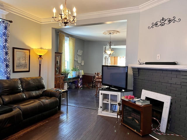 living room featuring a brick fireplace, crown molding, dark hardwood / wood-style flooring, and a chandelier