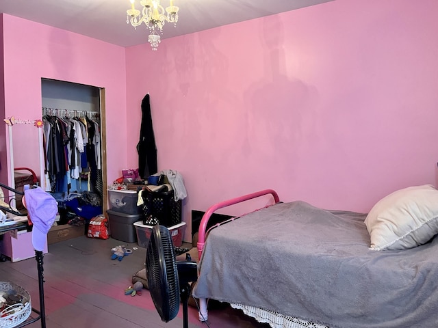 bedroom featuring wood-type flooring, an inviting chandelier, and a closet