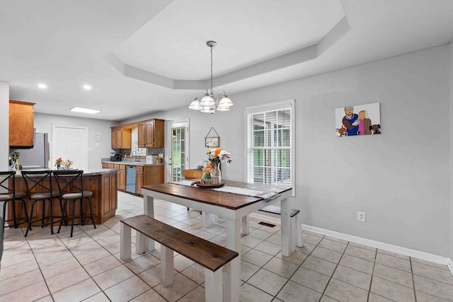 tiled dining space with a raised ceiling and an inviting chandelier