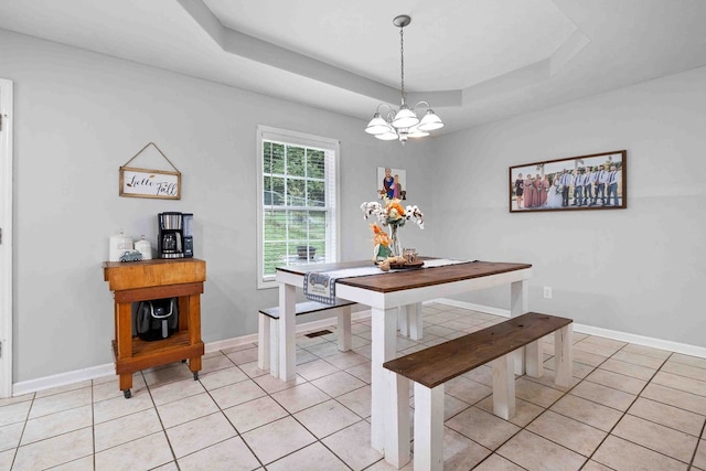 dining space featuring a notable chandelier, a raised ceiling, and light tile patterned flooring