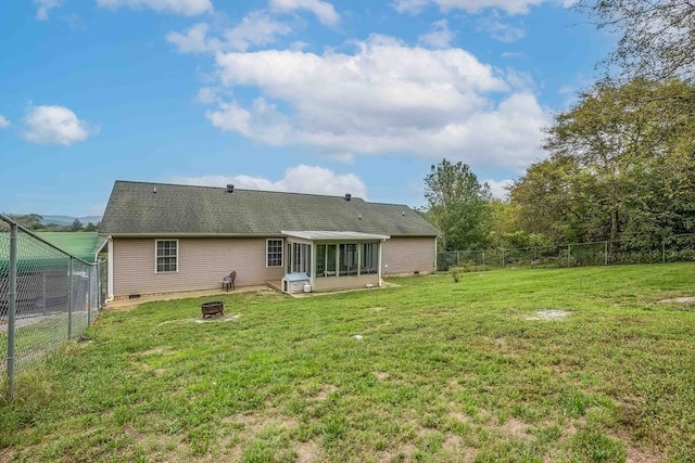 rear view of house featuring a sunroom, a fire pit, and a yard