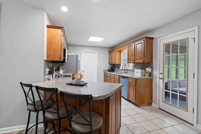 kitchen with kitchen peninsula, appliances with stainless steel finishes, sink, and a breakfast bar area