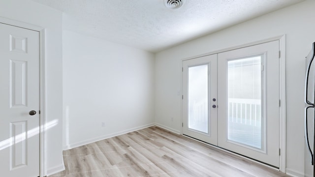 doorway featuring french doors, a textured ceiling, and light wood-type flooring