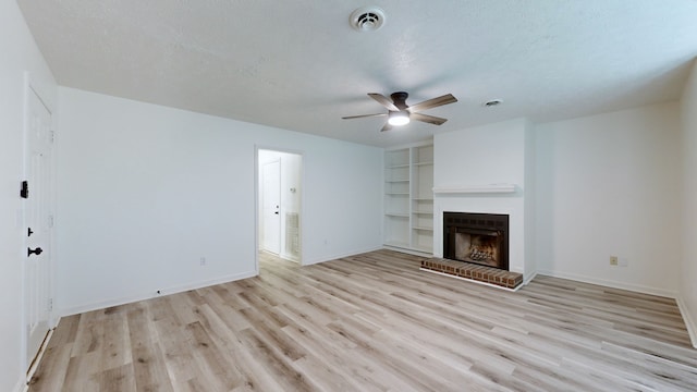 unfurnished living room with ceiling fan, a textured ceiling, light hardwood / wood-style flooring, and a fireplace