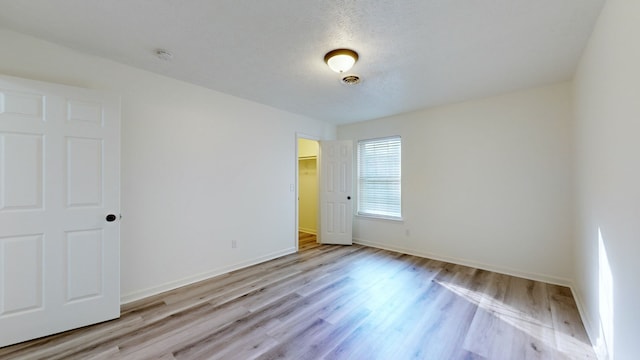 unfurnished room with a textured ceiling and light hardwood / wood-style flooring