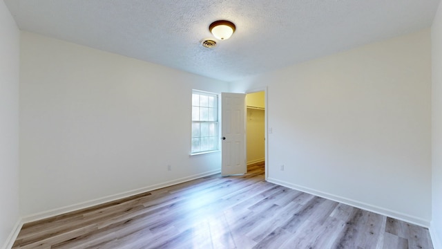 unfurnished room with a textured ceiling and light hardwood / wood-style flooring