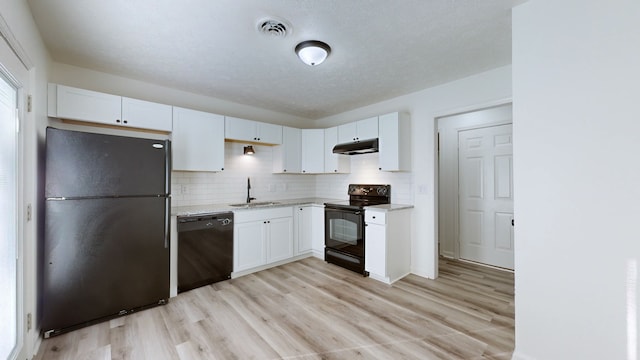 kitchen with decorative backsplash, white cabinets, light wood-type flooring, black appliances, and sink