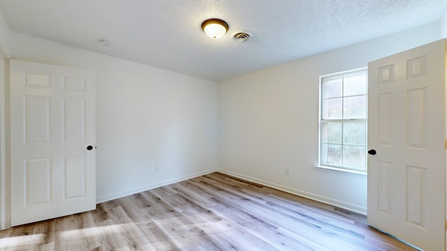 spare room featuring a textured ceiling and light wood-type flooring