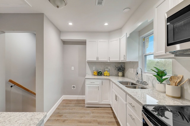 kitchen featuring white cabinets, light stone counters, and sink