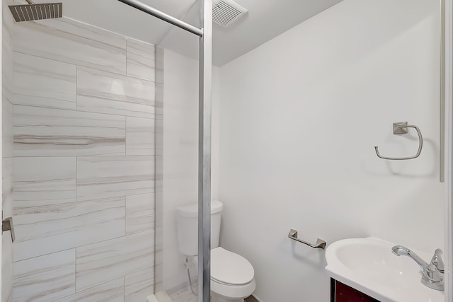 bathroom featuring tiled shower, vanity, and toilet