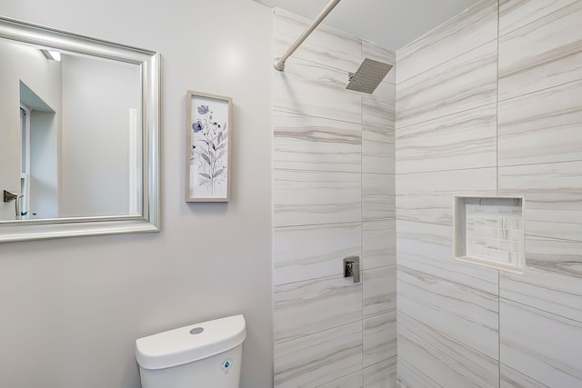 bathroom with a tile shower and toilet