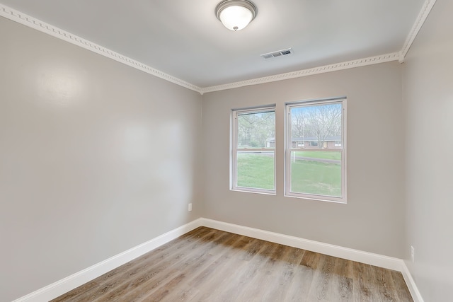 empty room with crown molding and light hardwood / wood-style floors