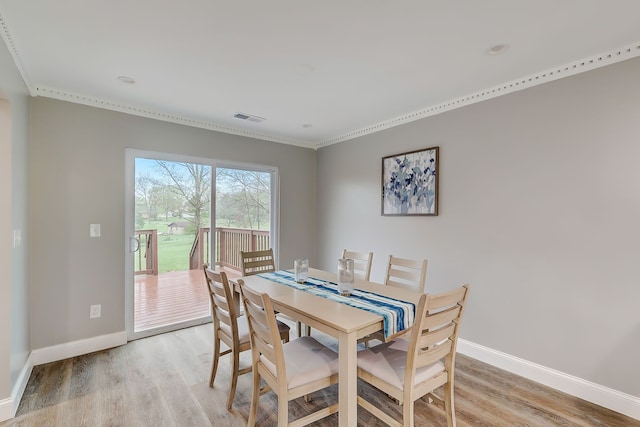 dining room featuring crown molding and light hardwood / wood-style floors