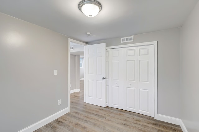 unfurnished bedroom featuring light hardwood / wood-style flooring and a closet