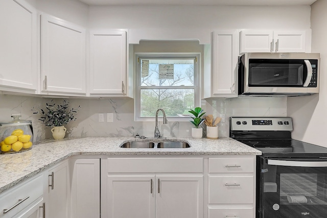 kitchen with light stone counters, sink, white cabinets, decorative backsplash, and appliances with stainless steel finishes