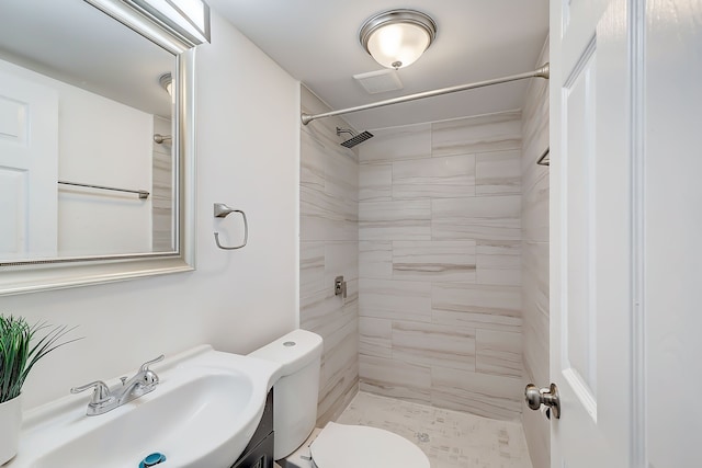 bathroom featuring vanity, toilet, and tiled shower